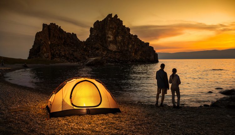 夕暮れの海辺でテントを貼る親子